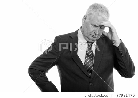 Studio shot of stressed mature businessman looking down while thinking Studio shot of stressed mature businessman looking down while thinking 57981479