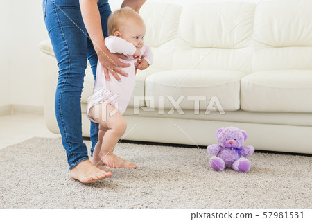Little baby girl first steps with the help of mom Little baby girl first steps with the help of mom 57981531