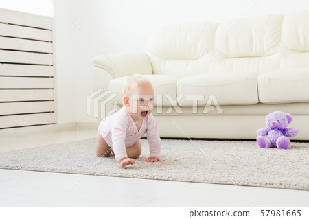 Adorable baby girl learning to crawl in white sunny room. Adorable baby girl learning to crawl in white sunny room. 57981665