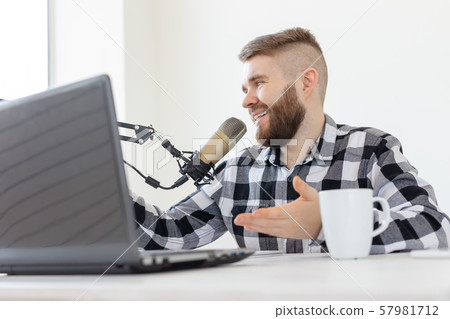 Radio, DJ, blogging and people concept - Smiling man sitting in front of microphone, host at radio 57981712