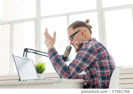 Radio, DJ, blogging and people concept - Smiling man sitting in front of microphone, host at radio Radio, DJ, blogging and people concept - Smiling man sitting in front of microphone, host at radio 57981766