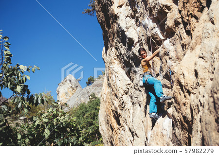 Woman climbs a rock. 57982279