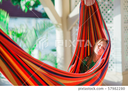 Adorable little girl on tropical vacation relaxing in hammock 57982280