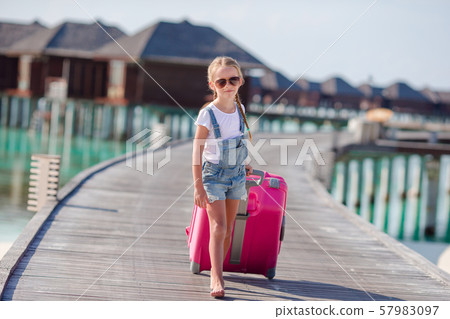 Little adorable girl with big luggage during summer vacation Little adorable girl with big luggage during summer vacation 57983097