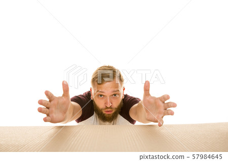 Young man opening the biggest postal package isolated on white Young man opening the biggest postal package isolated on white 57984645