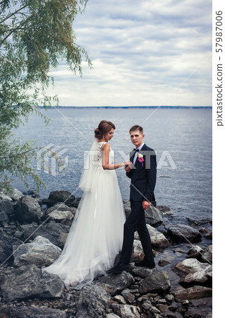 A pair of young newlyweds on the stones by the big river 57987006