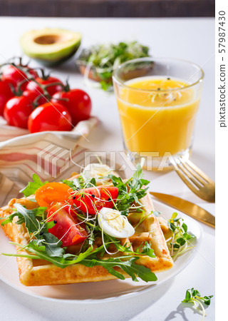 Fresh baked sweet belgian waffles with eggs, tomatoes, micro green and avocado served on a plate Fresh baked sweet belgian waffles with eggs, tomatoes, micro green and avocado served on a plate 57987430