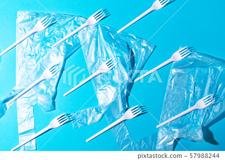 White plastic forks and bags on blue background. White plastic forks and bags on blue background. 57988244