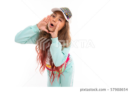 Teenage girl in sparkling clothes and fashionable cap shouting someting with her hands near her 57988654