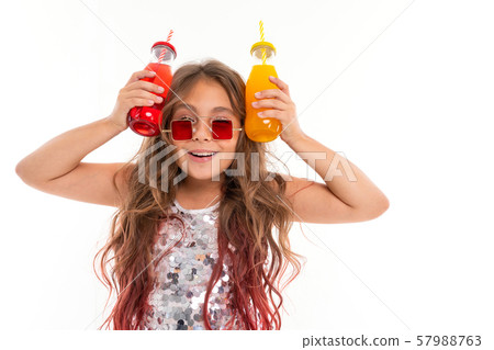 Happy girl in glittery dress and stylish square red sunglasses playing with two glass bottles with 57988763