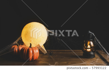 Halloween decorations with pumpkin,lantern and the moon on wooden table with a black backdrop. 57993122