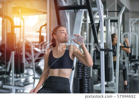 Beautiful young woman drinks water in gym. Sports 57994682