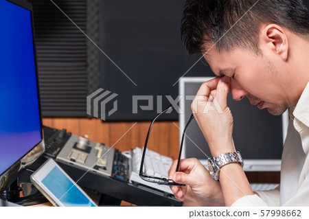 asian male computer engineer with eye pain touching his eyes and holding glasses 57998662