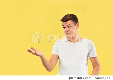 Caucasian young man's half-length portrait on yellow background 58001734