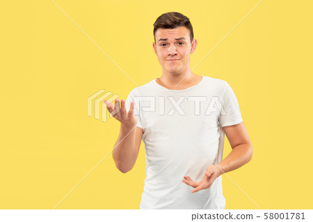 Caucasian young man's half-length portrait on yellow background 58001781