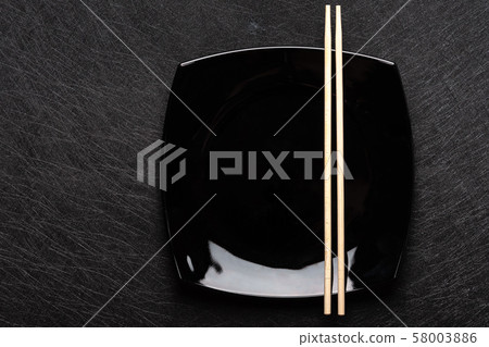 Empty black plate with chopsticks on dark background. Japanese food style. Top view with copy space Empty black plate with chopsticks on dark background. Japanese food style. Top view with copy space 58003886