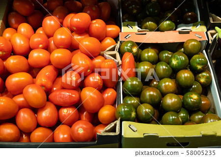 Close-up of mellow red tomatoes and green variety of tomatoes on counter of grocery store 58005235