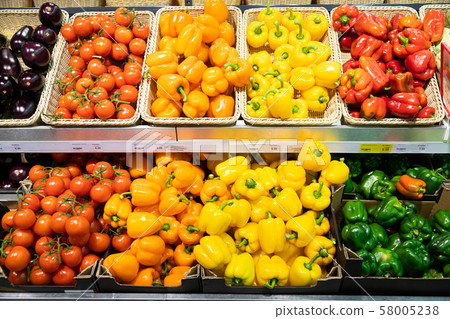 Grocery store counter with wicker baskets and lug boxes with tomatoes, squash, orange and yellow 58005238