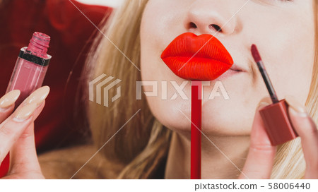 Woman applying lipstick or lip gloss 58006440