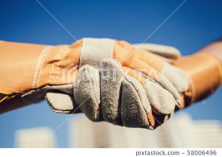builders hands in gloves greeting each other 58006496