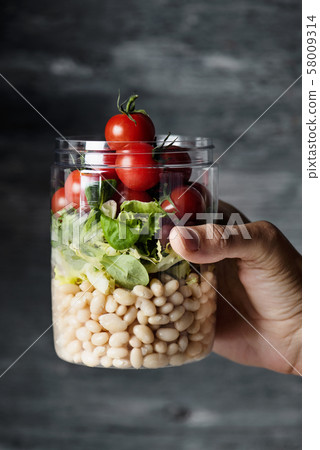 man with a jar salad in his hand. man with a jar salad in his hand. 58009314