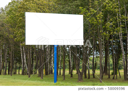 Mock of white blank advertising board standing along road against trees Mock of white blank advertising board standing along road against trees 58009396