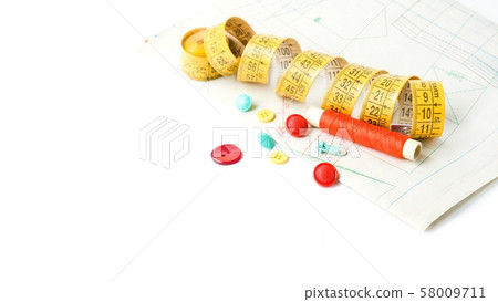 Sewing supplies on white sewing thread, scissors, pattern, centimeter, buttons Sewing supplies on white sewing thread, scissors, pattern, centimeter, buttons 58009711