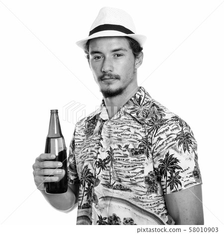 Studio shot of young handsome tourist man holding bottle of beer isolated against white background 58010903