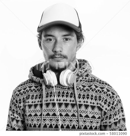 Studio shot of young handsome man wearing cap and headphones around neck isolated against white Studio shot of young handsome man wearing cap and headphones around neck isolated against white 58011090