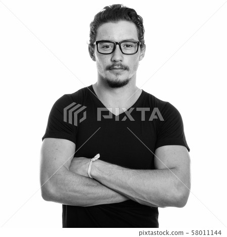 Studio shot of young handsome man with arms crossed while wearing eyeglasses isolated against white 58011144