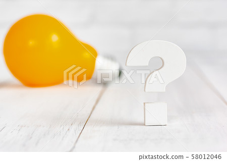 Question mark with light bulb on white wood table 58012046