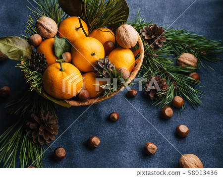 Hazelnuts, walnuts and tangerines decorated with Christmas branches and pine cones Hazelnuts, walnuts and tangerines decorated with Christmas branches and pine cones 58013436