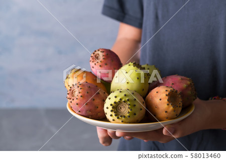 Female hands hold a plate with ripe fresh fruits 58013460