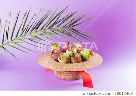 Opuntia fruit in a straw hat with a palm leaf on a 58013468