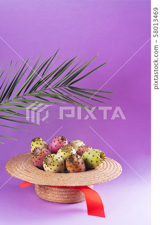 Opuntia fruit in a straw hat with a palm leaf on a 58013469
