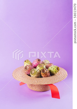 Opuntia fruit in a straw hat on a trendy purple 58013470