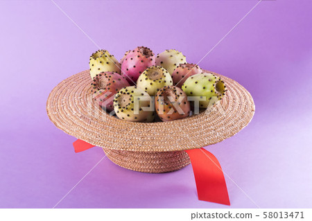 Opuntia fruit in a straw hat on a trendy purple 58013471