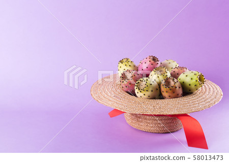 Opuntia fruit in a straw hat on a trendy purple 58013473