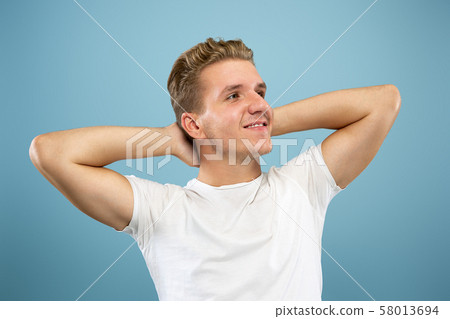 Caucasian young man's half-length portrait on blue background 58013694
