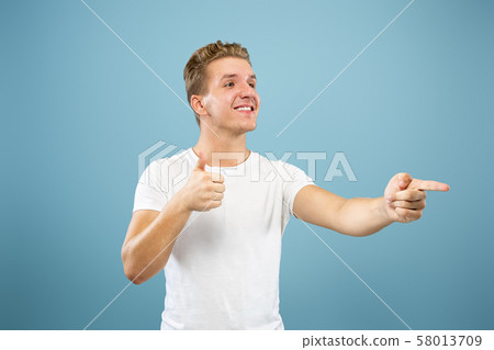 Caucasian young man's half-length portrait on blue background 58013709