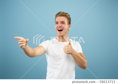 Caucasian young man's half-length portrait on blue background 58013713