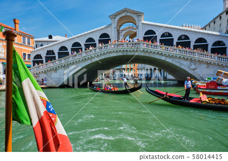 Italian maritime flag with Rialto bridge with gondolas in the bacground. Grand Canal, Venice, Italy Italian maritime flag with Rialto bridge with gondolas in the bacground. Grand Canal, Venice, Italy 58014415