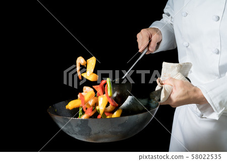 Cook shaking a wok 58022535