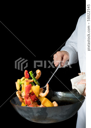 Cook shaking a wok 58022545