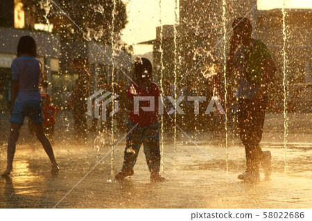 Happy kids have fun playing in city water fountain 58022686