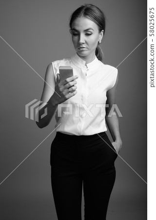Portrait of young beautiful businesswoman against gray background Portrait of young beautiful businesswoman against gray background 58025675