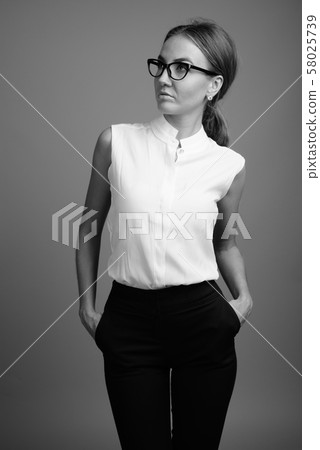 Portrait of young beautiful businesswoman against gray background 58025739