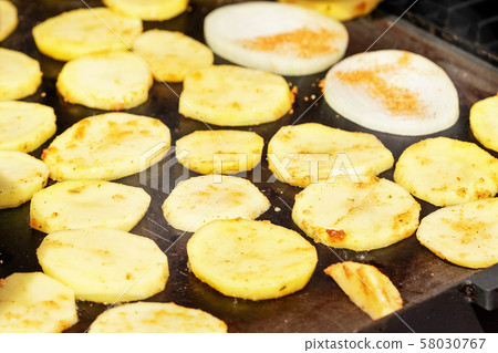 Potatoes cut to thin slices grilled on electric grill 58030767