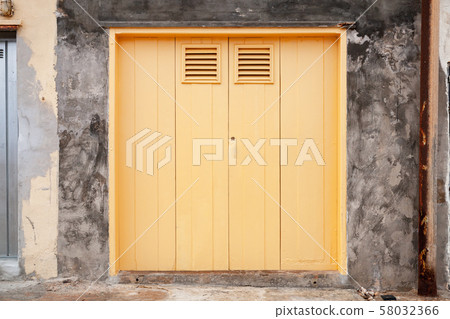 Closed old yellow gate in grungy stone wall 58032366