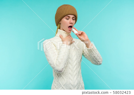 Sick young woman in scarf and hat use nasal spray Sick young woman in scarf and hat use nasal spray 58032423